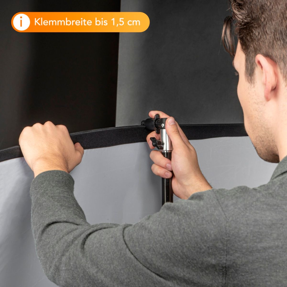 Eine Person, die einen Reflektorschirm einstellt, mit Text, der eine Klemmbreite von bis zu 1,5 cm angibt.