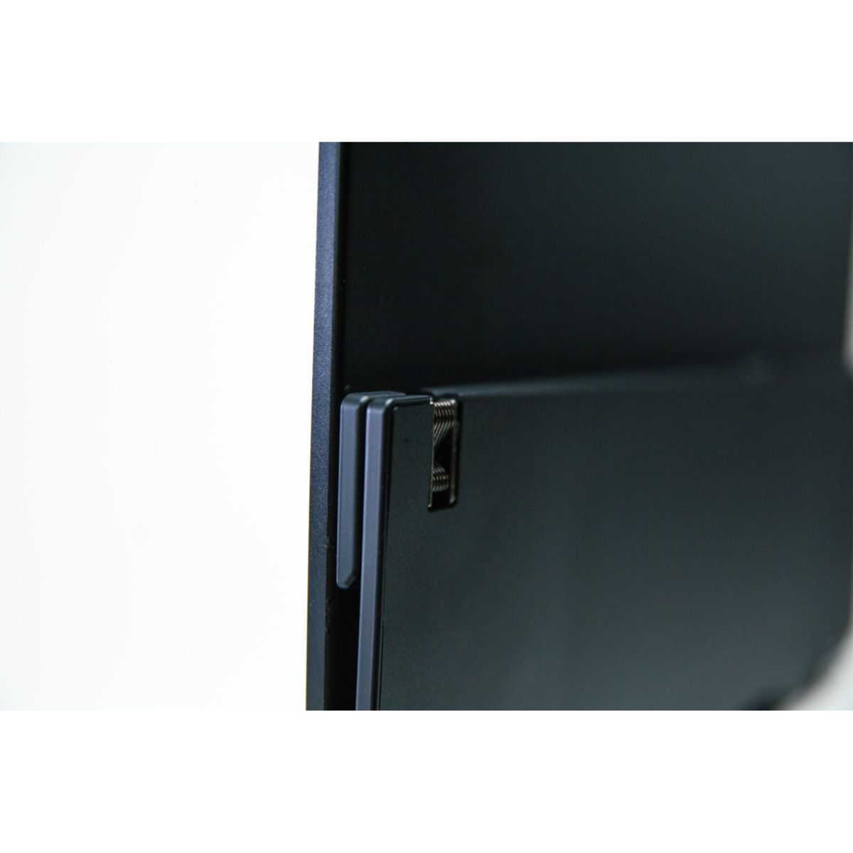 Zbliżenie tylnej strony czarnego laptopa, pokazujące zawias i niektóre komponenty wewnętrzne.