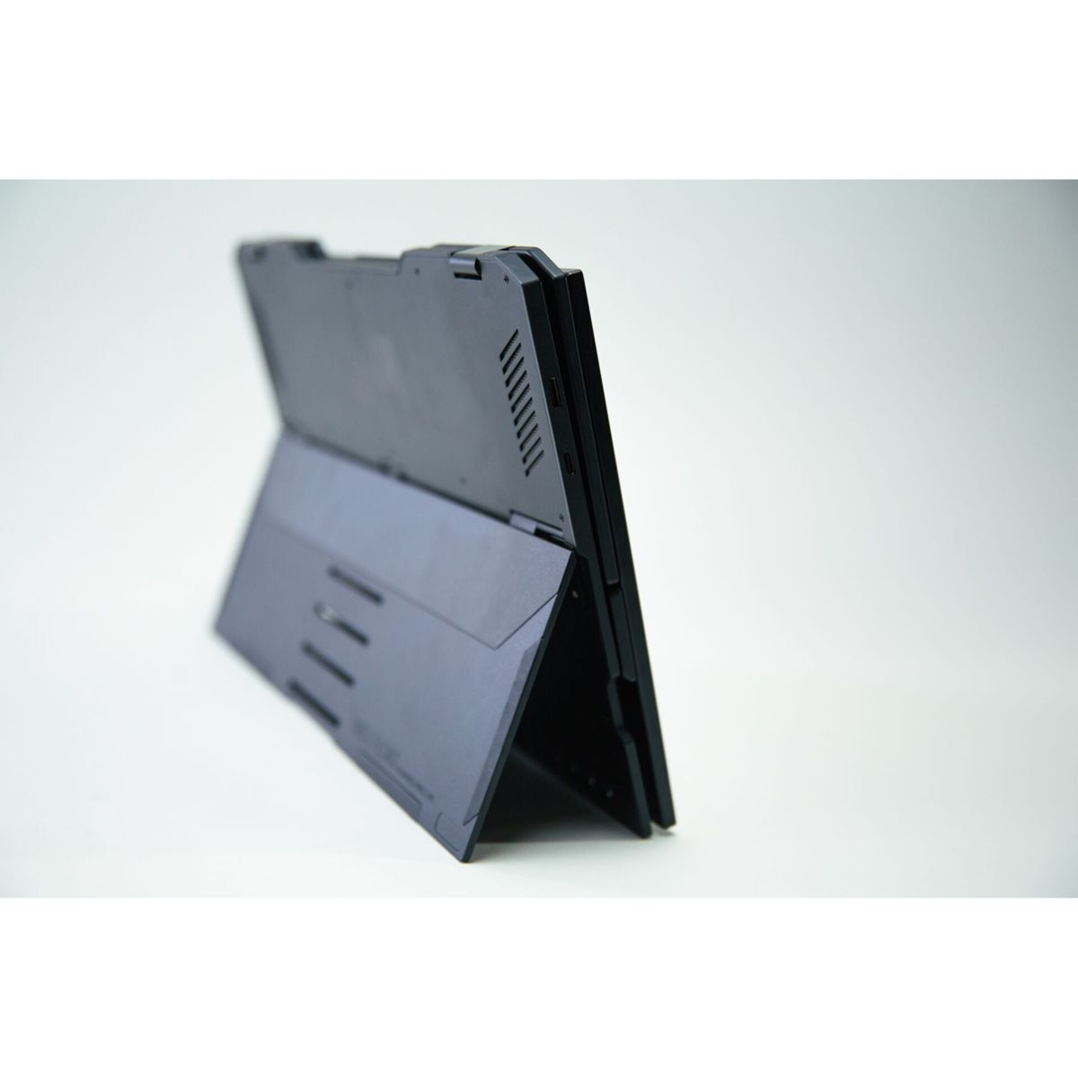 Czarny laptop, widok z boku. Ekran jest otwarty, a urządzenie jest lekko przechylone.