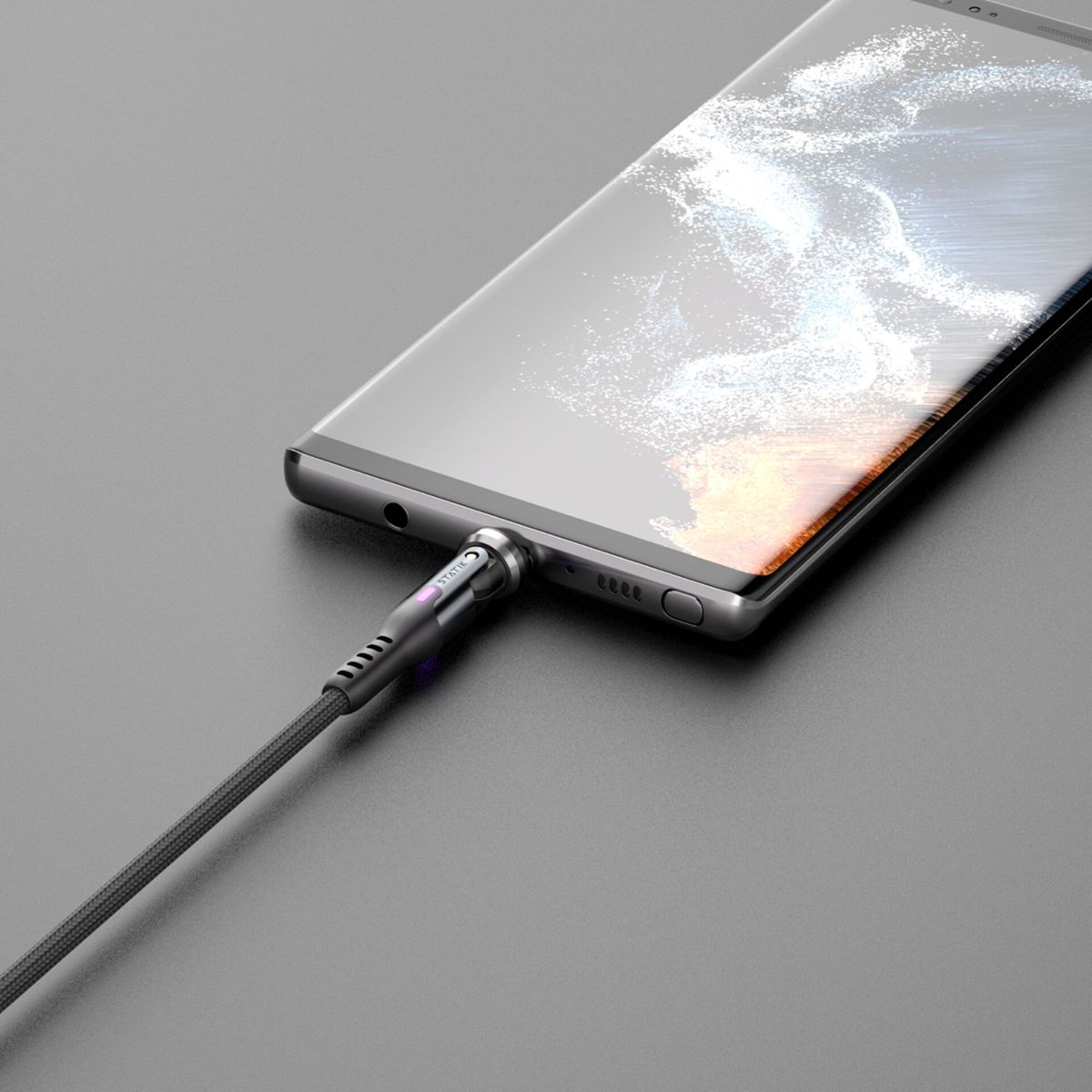 Ein Telefon wird mit einem Kabel aufgeladen. Das Kabel ist mit dem Telefon und einer grauen Oberfläche verbunden.