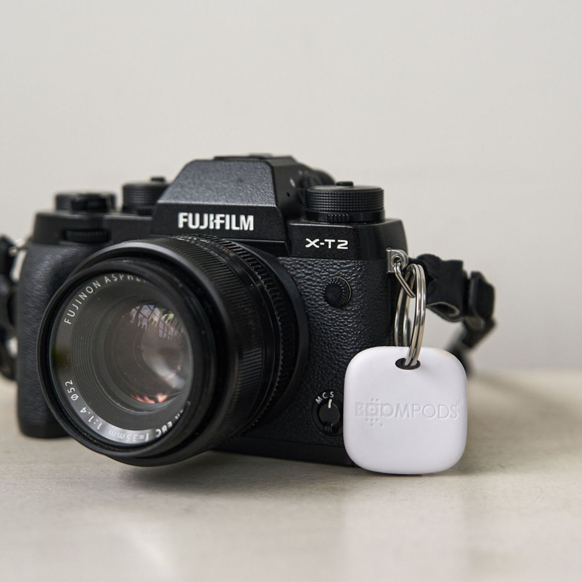 Una fotocamera con un'etichetta bianca allegata. La fotocamera è nera, con un obiettivo e il marchio Fujifilm.