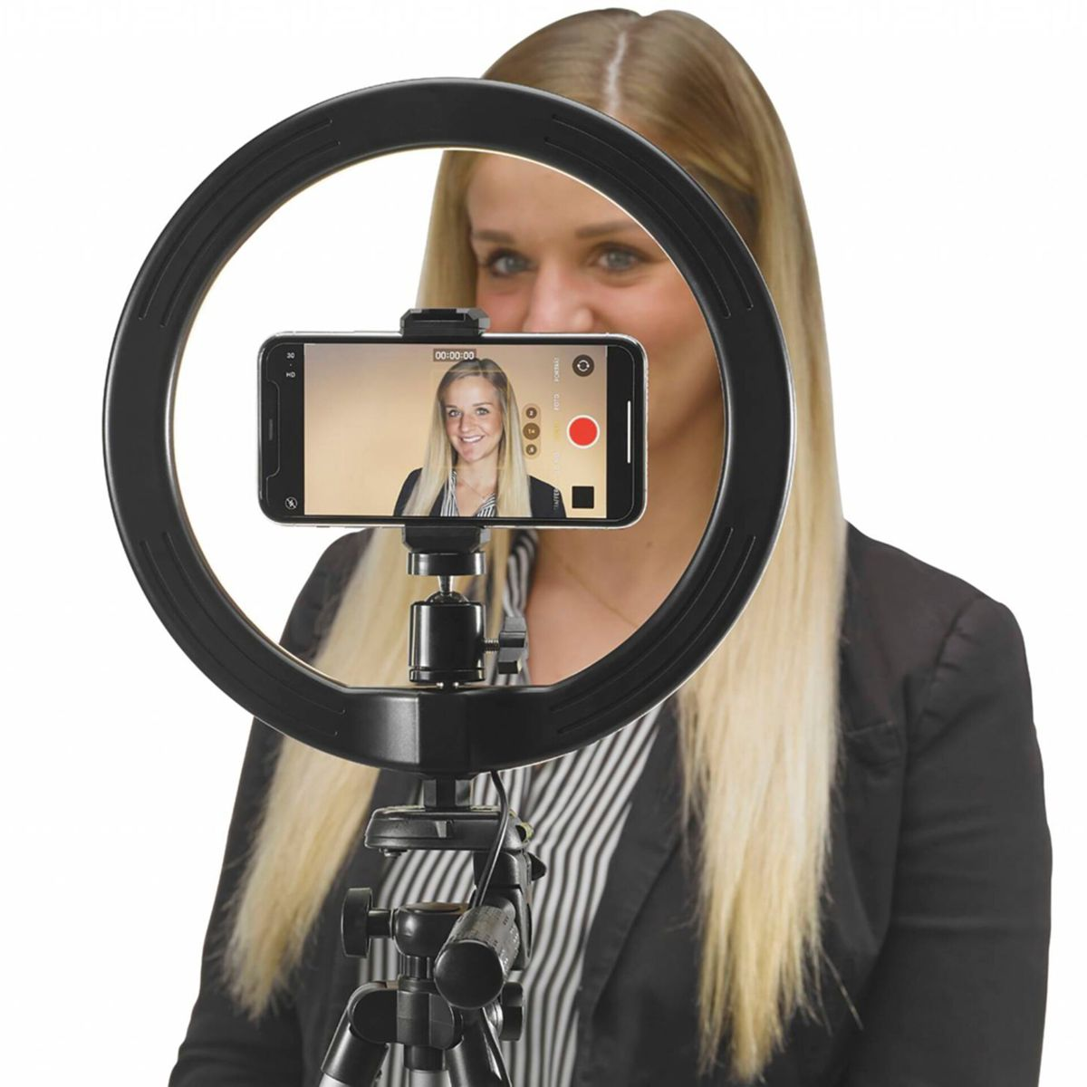 Eine Frau nimmt ein Video mit ihrem Telefon auf, das an einem Ringlicht befestigt ist. Das Telefon zeigt sie an.