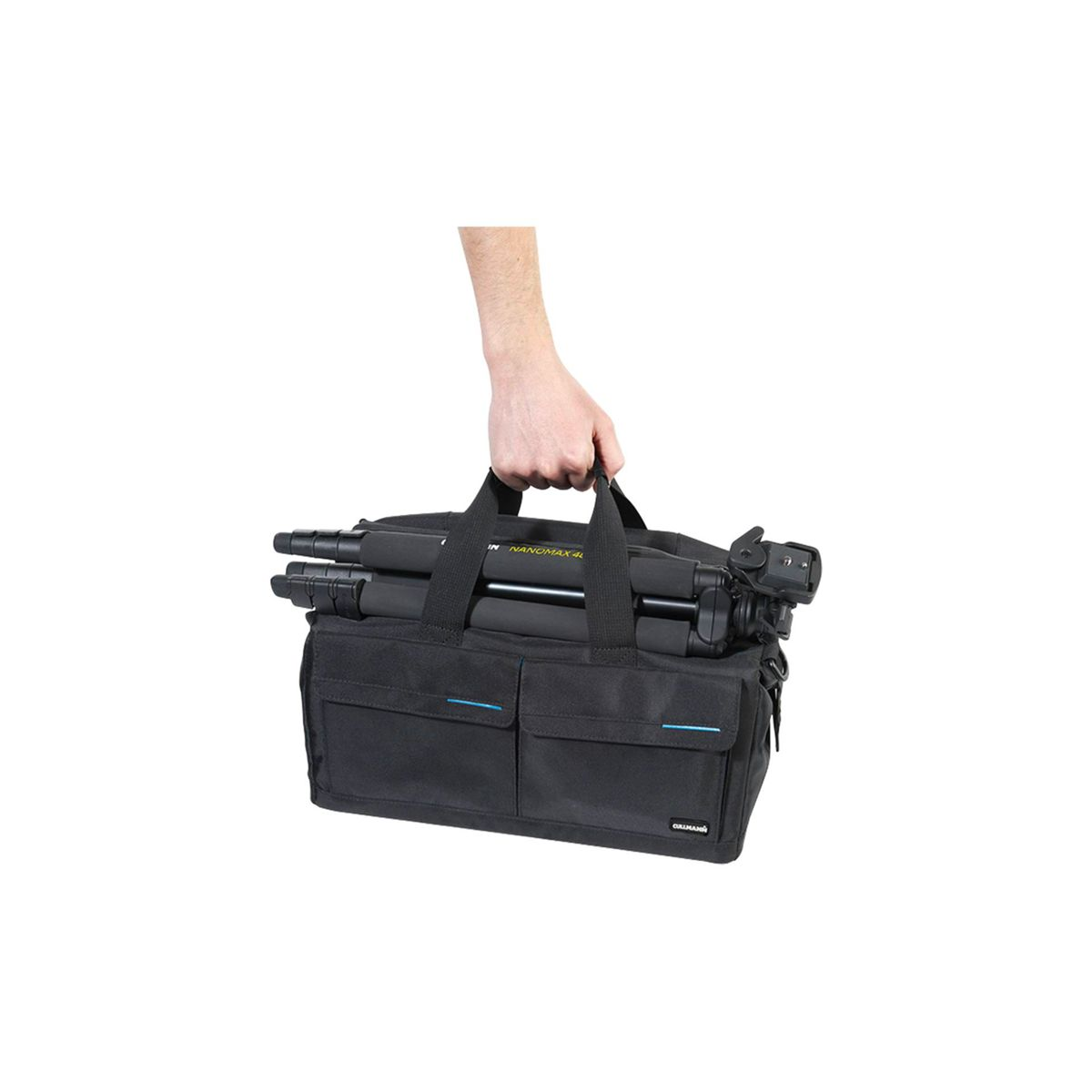 Eine Hand hält eine schwarze Stativtasche mit einem Stativ darin. Die Tasche hat Vordertaschen und einen Griff.