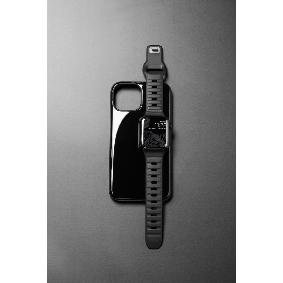 Telefon und Uhr auf dunkler Oberfläche, Uhr zeigt die Zeit an.