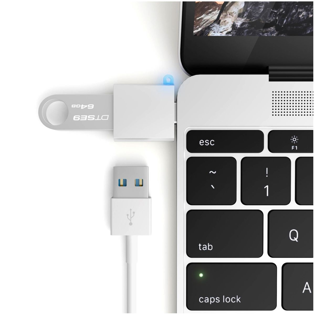 Un'unità USB argentata è collegata a un laptop. Sono visibili anche un cavo USB bianco e una tastiera.