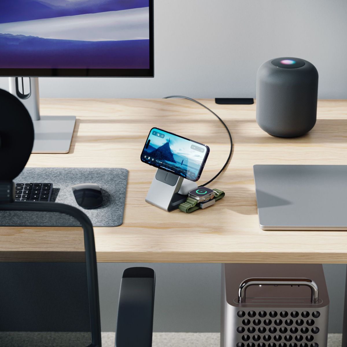 Schreibtisch-Setup mit Telefon, Uhr, Monitor, Lautsprecher und Laptop. Das Telefon wird geladen. Uhr auf einem Ladegerät.