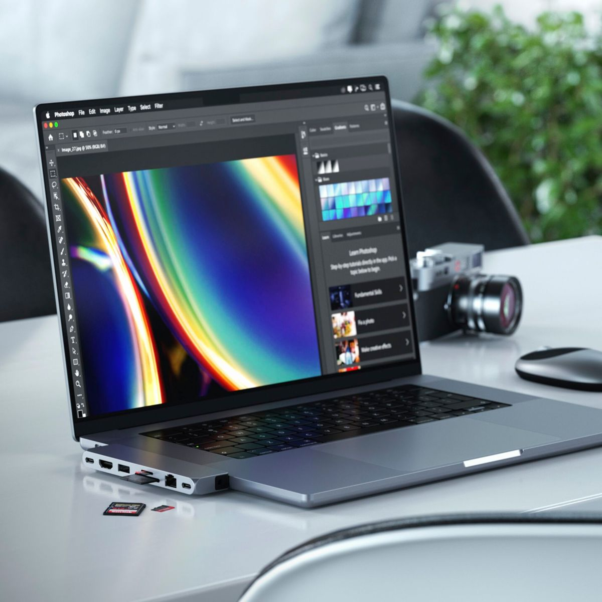 Laptop mit angeschlossenem Hub. Der Bildschirm zeigt eine Fotoschnittstellensoftware. Eine Kamera ist in der Nähe.