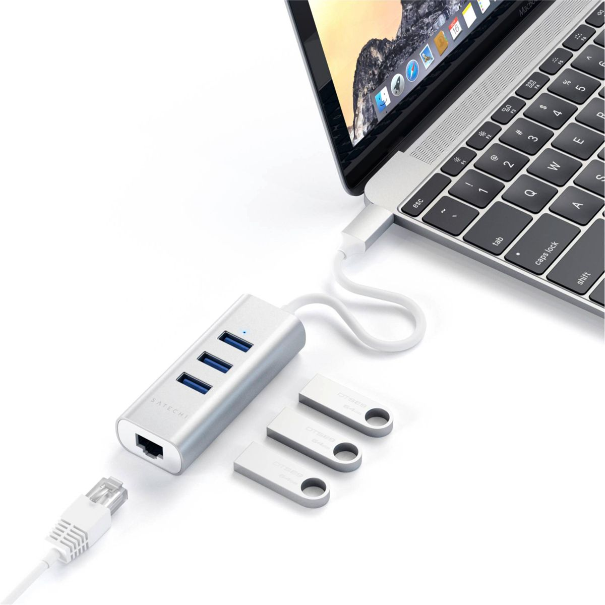 Laptop collegato a un hub argentato con porte USB e Ethernet. Pen drive nelle vicinanze.