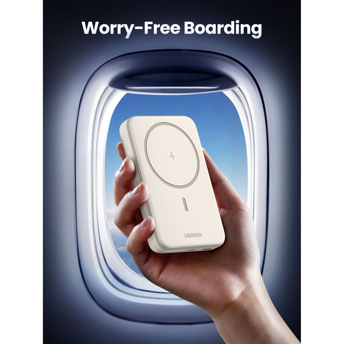 Dłoń trzymająca biały power bank na tle okna samolotu. Power bank ma na sobie okrąg.