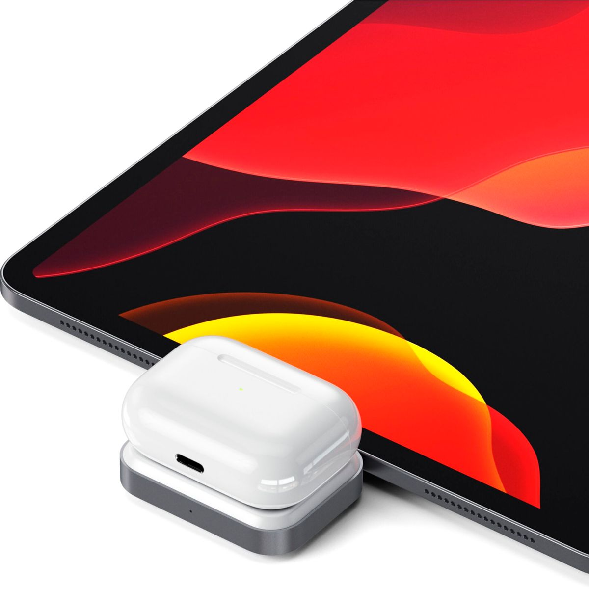 Un cargador inalámbrico blanco con AirPods Pro encima, colocado frente a una tableta.