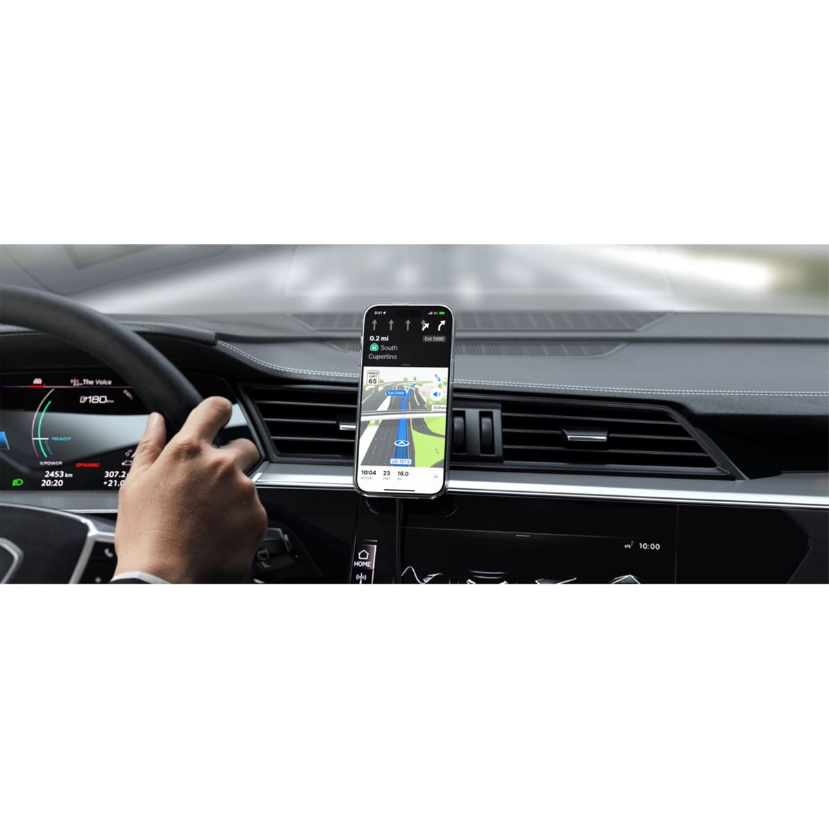 Un teléfono está montado en el salpicadero de un coche, mostrando una app de navegación. Una mano está en el volante.