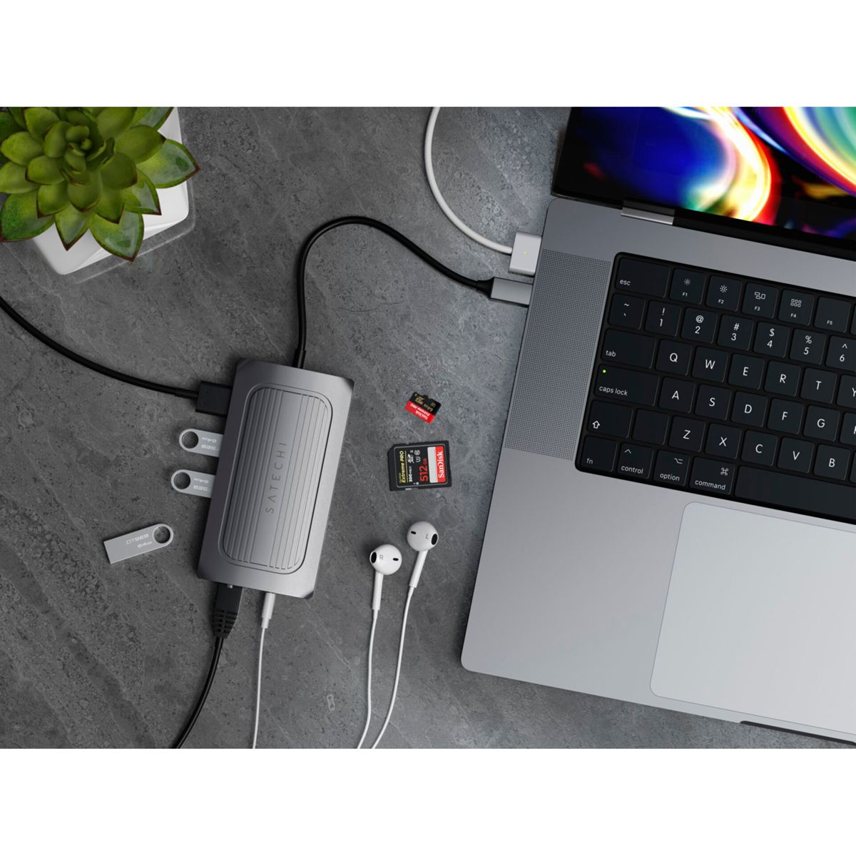 Laptop mit Hub, SD-Karten und USB-Laufwerken. Ohrhörer und Zubehör auf dem Schreibtisch.