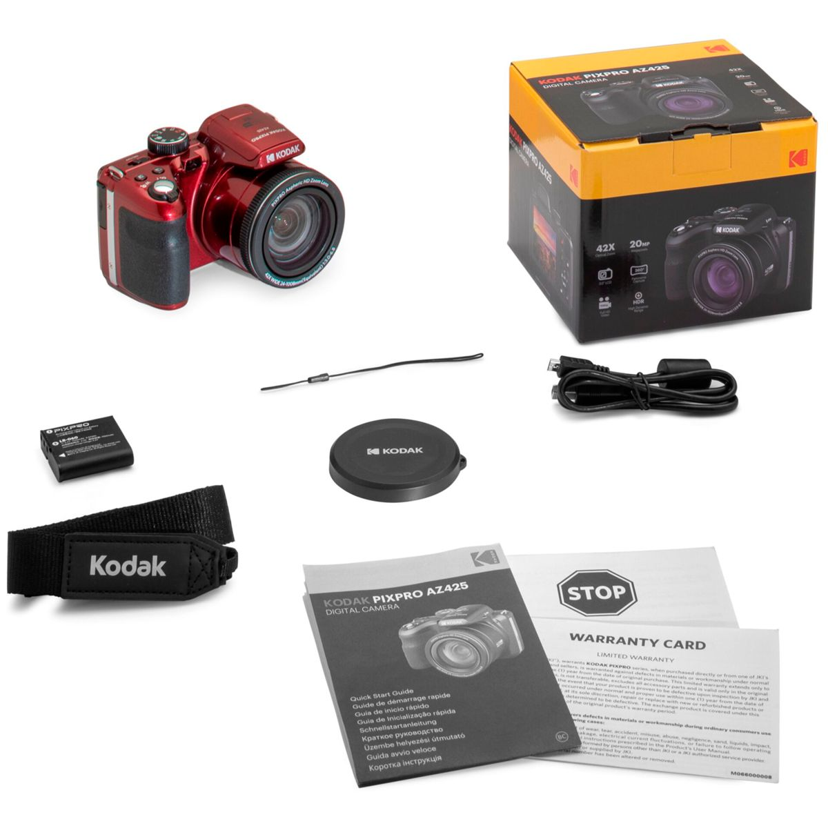 Czerwony aparat, pudełko, bateria, osłona obiektywu, pasek i instrukcje na stole.