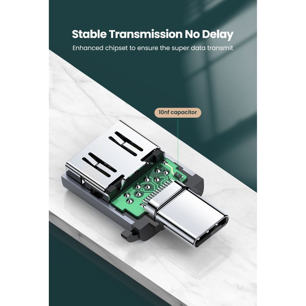 Zbliżenie adaptera USB-C z odsłoniętą płytką drukowaną i kondensatorem 10nf. Na marmurowej powierzchni.