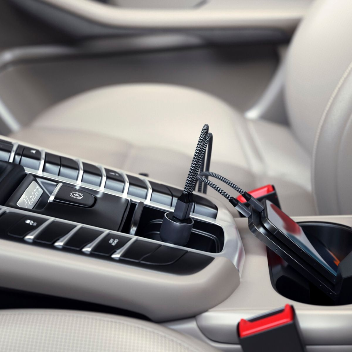 Un telefono si ricarica nella console di un'auto. Un cavo grigio collega il telefono a un laptop.