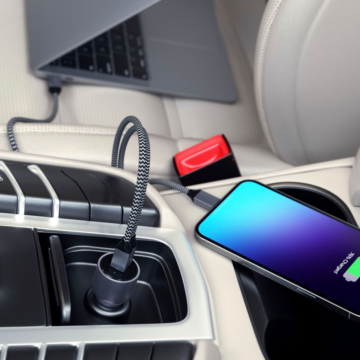 All'interno di un'auto, un telefono si ricarica con un cavo grigio collegato a un laptop nella console dell'auto.