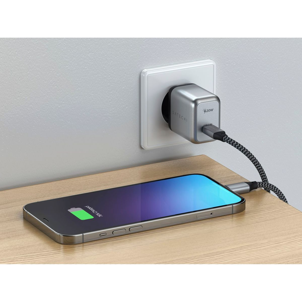 Telefon lädt auf einem Holztisch mit einem Ladegerät, das in eine Steckdose gesteckt ist.