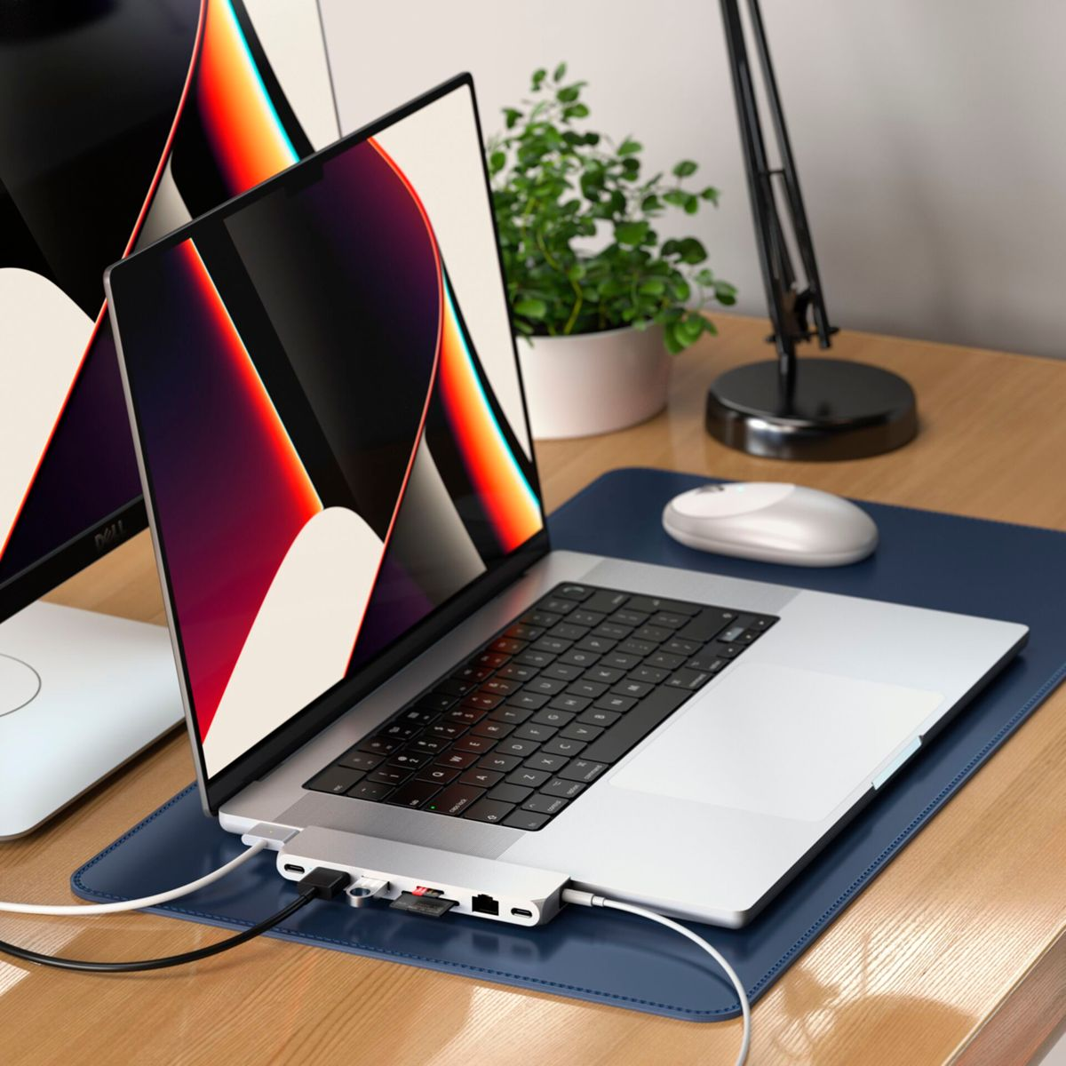 Laptop auf einem Schreibtisch mit zwei Monitoren, Maus und Hub. Kabel sind mit dem Laptop verbunden.