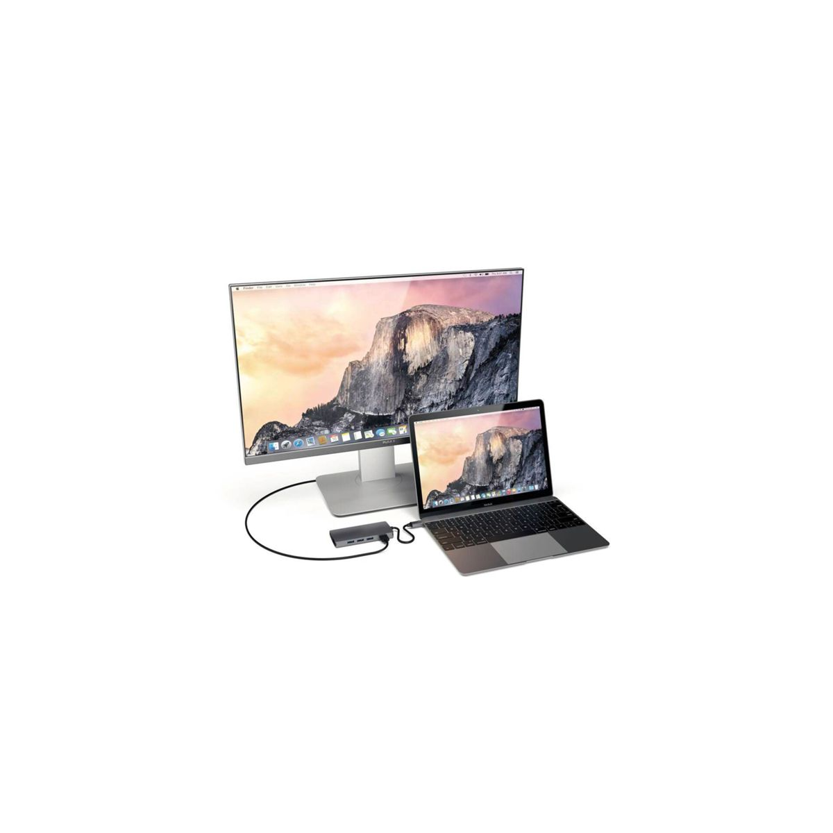 Ein Monitor und ein Laptop auf einer weißen Oberfläche. Ein Hub ist mit beiden Geräten verbunden. Gut beleuchtet, sauberes Setup.