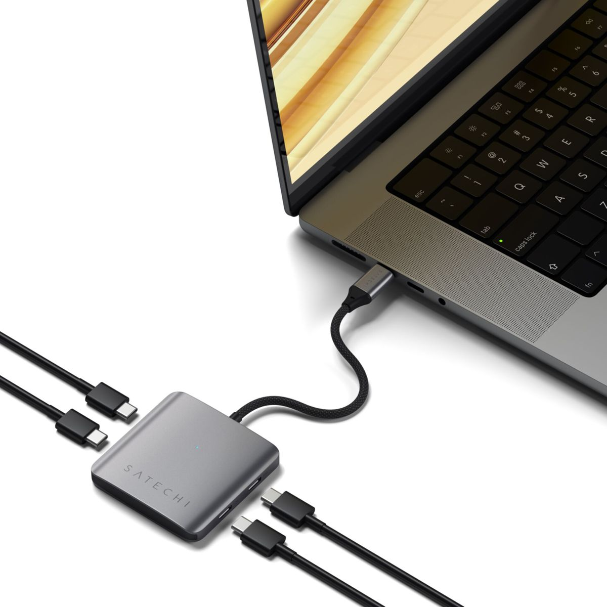 Laptop podłączony do szarego huba z podłączonymi kablami USB.
