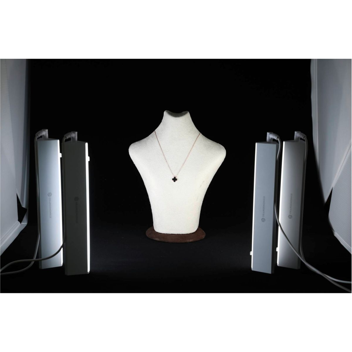 Un collar en un maniquí, iluminado por luces de estudio sobre un fondo negro.