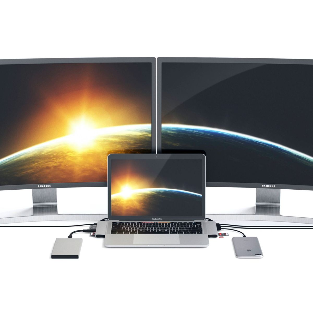 A laptop connected to two monitors, an external hard drive, and a phone. The setup is on a white surface.