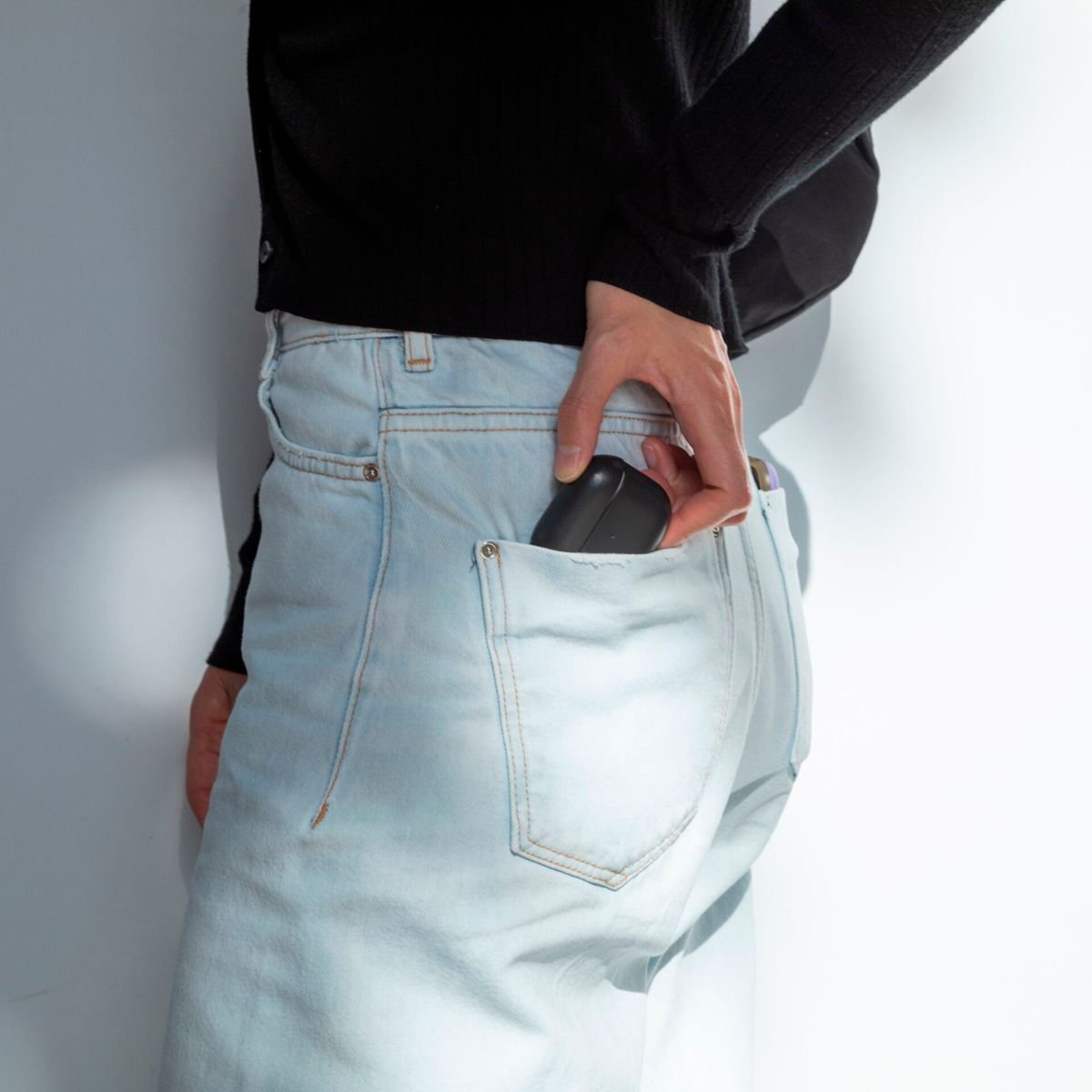 Un étui AirPods noir est placé dans la poche arrière d'un jean.