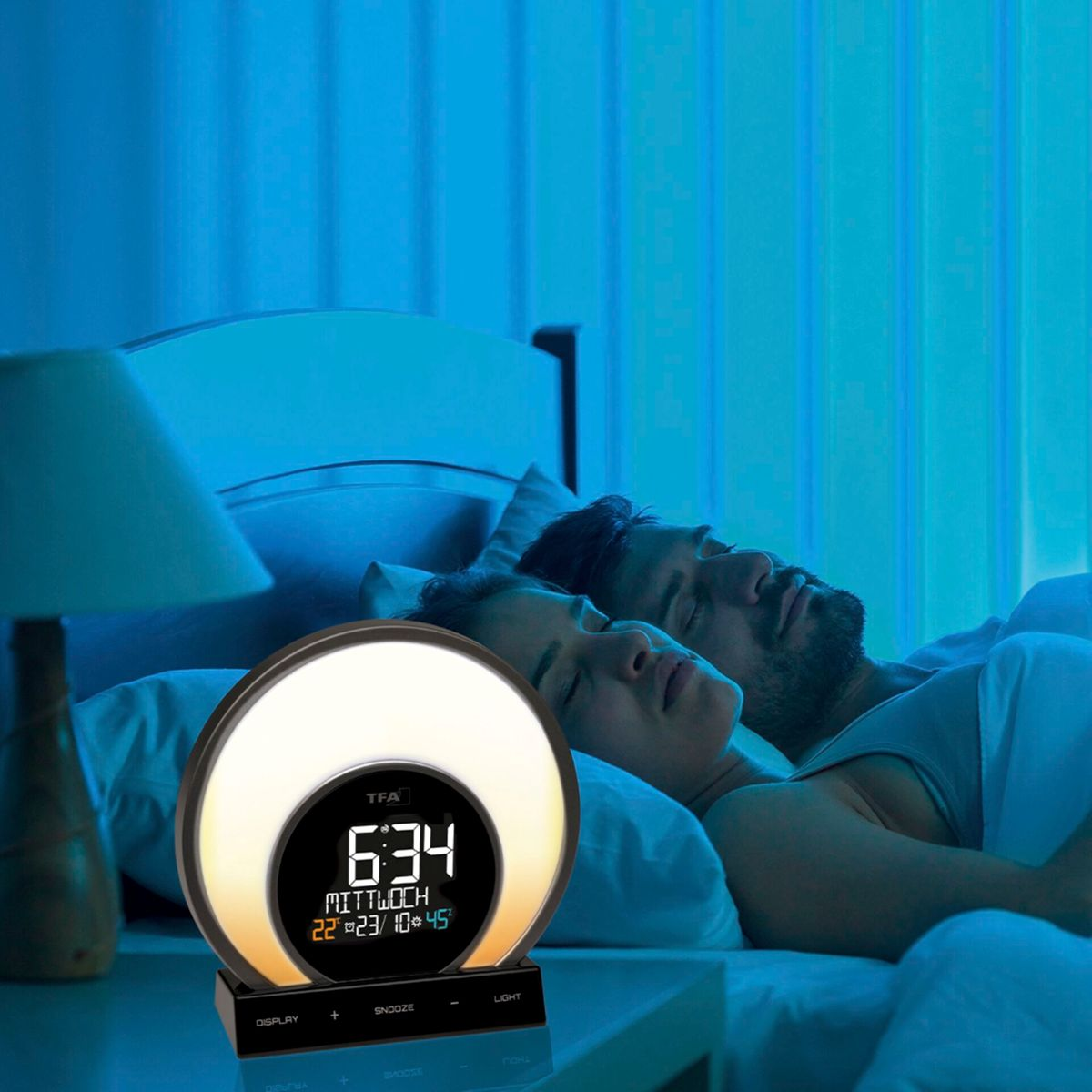 Ein Paar schläft im Bett mit einem Wecker auf dem Nachttisch. Die Uhr zeigt Zeit und Datum an.