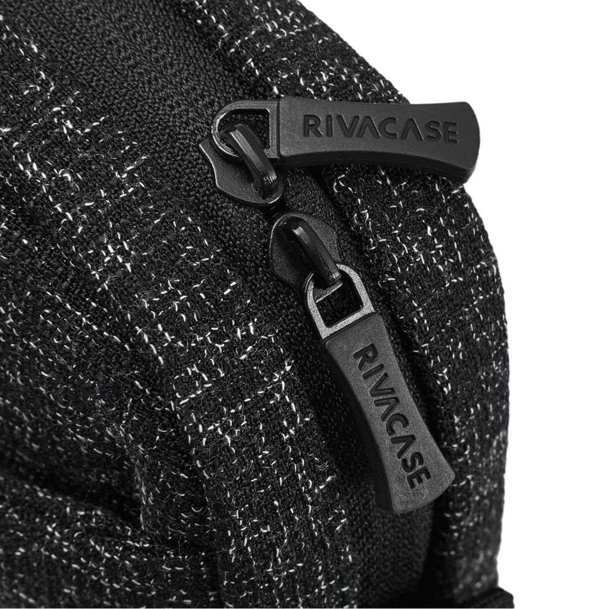 Nahaufnahme einer schwarzen Tasche mit zwei Reißverschlüssen, beide mit RIVACASE beschriftet.