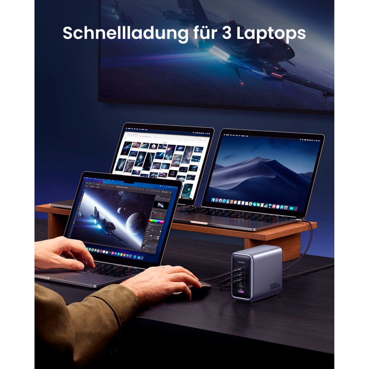 Trzy laptopy ładują się za pomocą srebrnej ładowarki. Tło przedstawia statek kosmiczny.