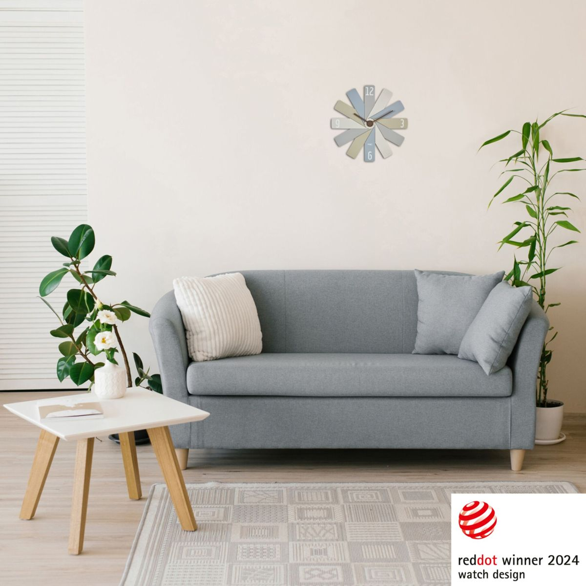 Wohnzimmerszene mit grauem Sofa, Uhr, Pflanzen und einem Red Dot Award.