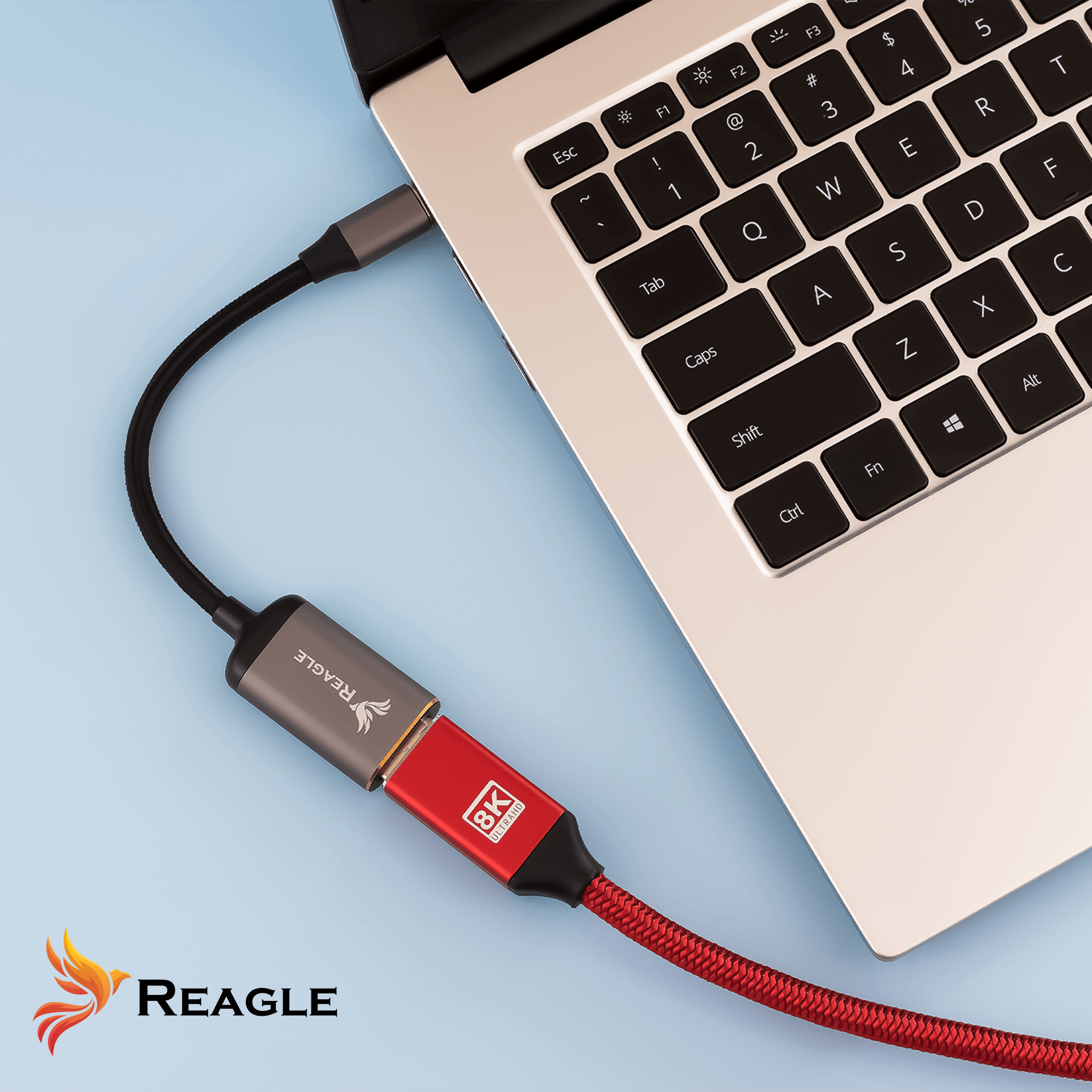 Laptop jest podłączony do adaptera USB-C do HDMI. Kabel jest czerwono-czarny. Pokazano logo 'REAGLE'.