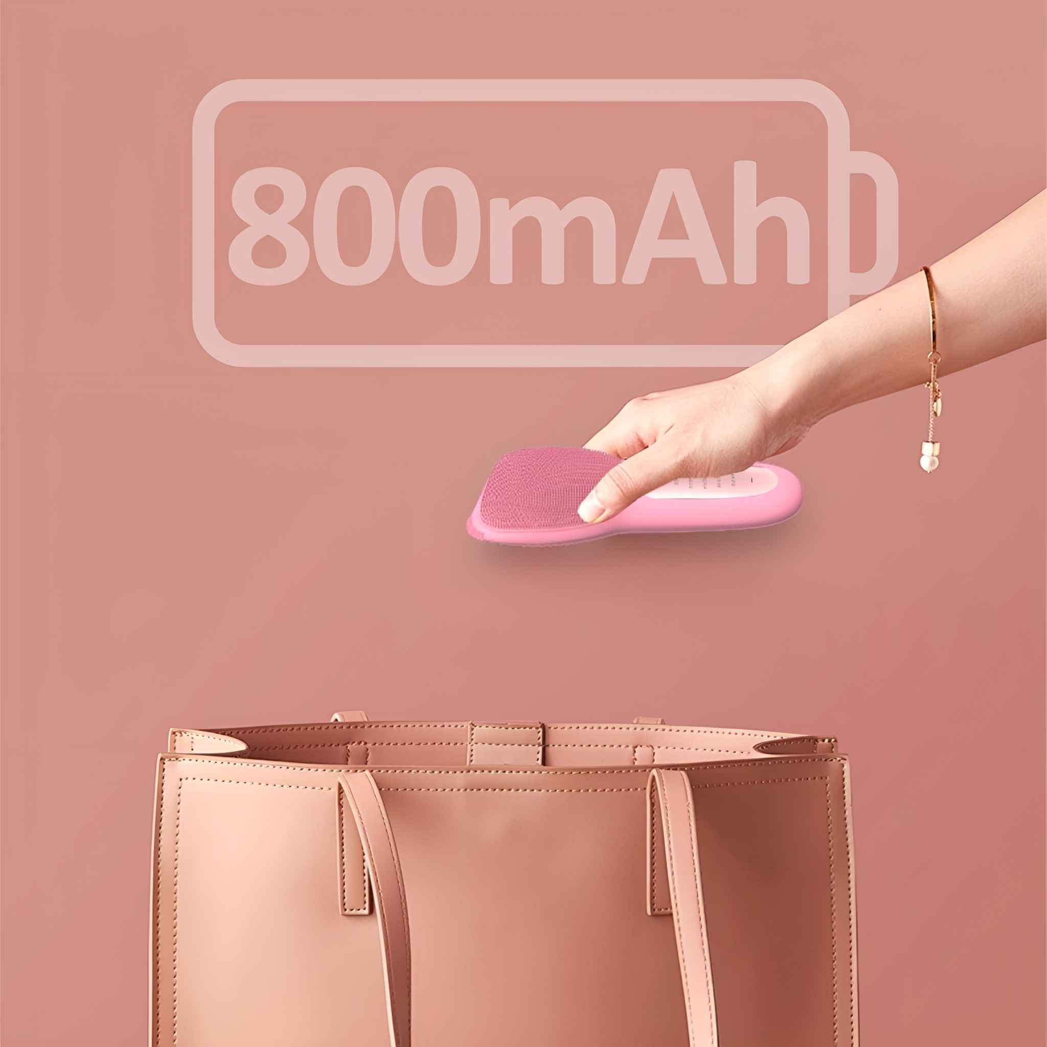 Die Hand einer Frau, die eine rosa Gesichtsbürste über einer rosa Handtasche hält. Der Text '800mAh' ist im Hintergrund.