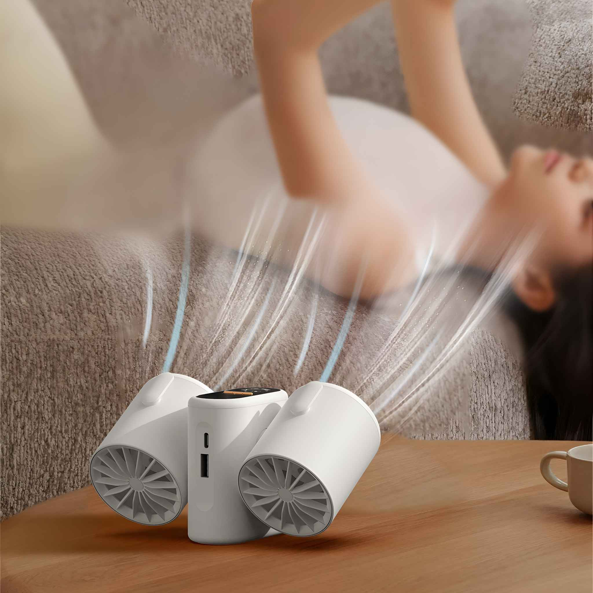 Drei weiße Ventilatoren, zwei nach außen gerichtet, auf einem Tisch platziert, mit einer Person und einem Sofa im Hintergrund.