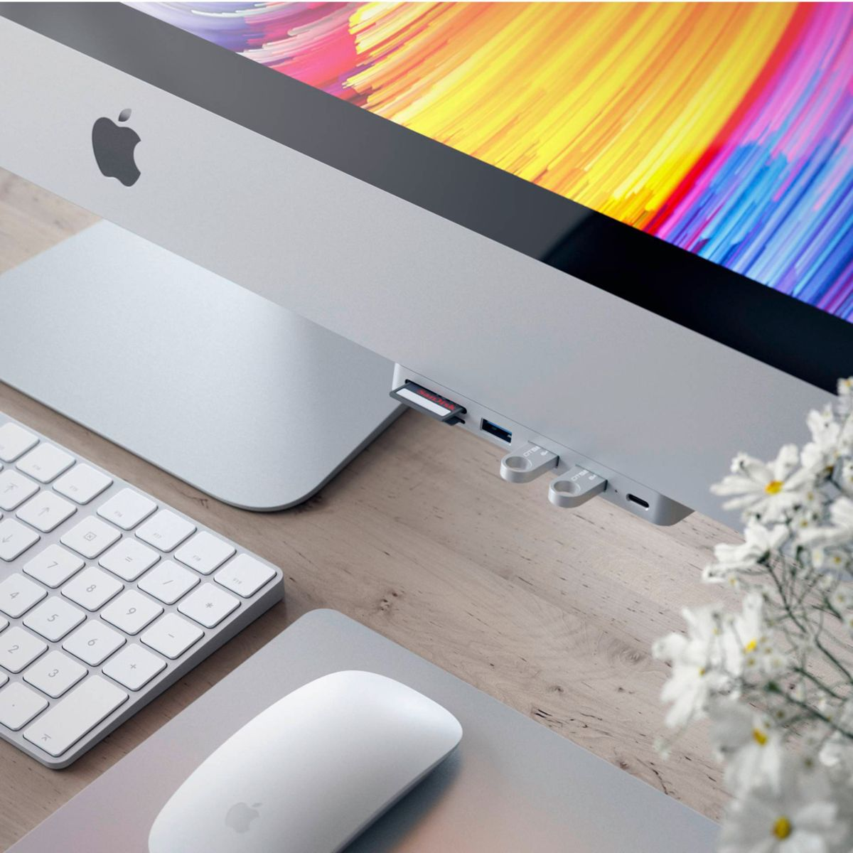 Nahaufnahme eines iMacs mit weißer Tastatur, Maus und mehrfarbigem Bildschirm. Zubehör ist angeschlossen.