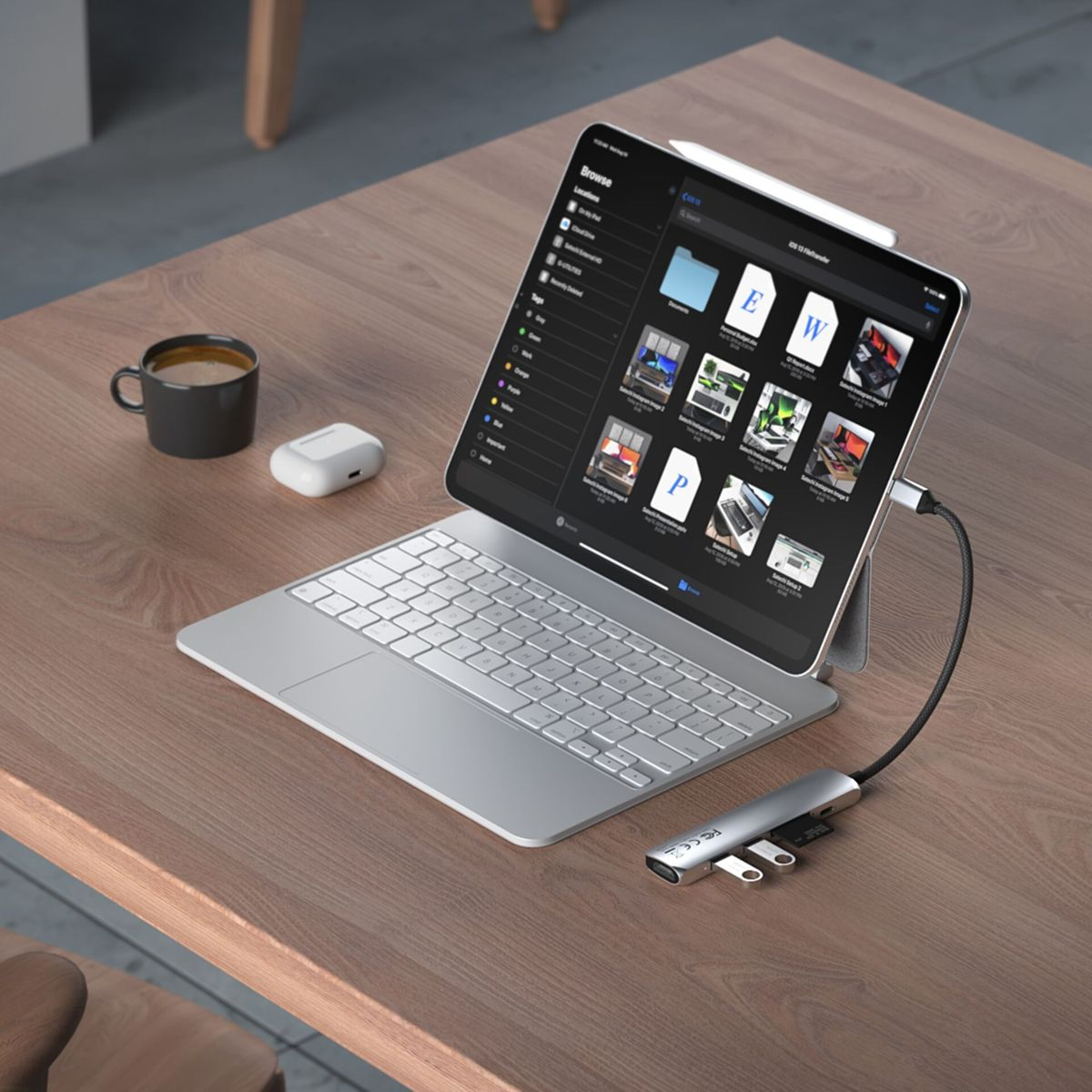 Un iPad con tastiera e hub collegato. Una tazza e una custodia sono sul tavolo.
