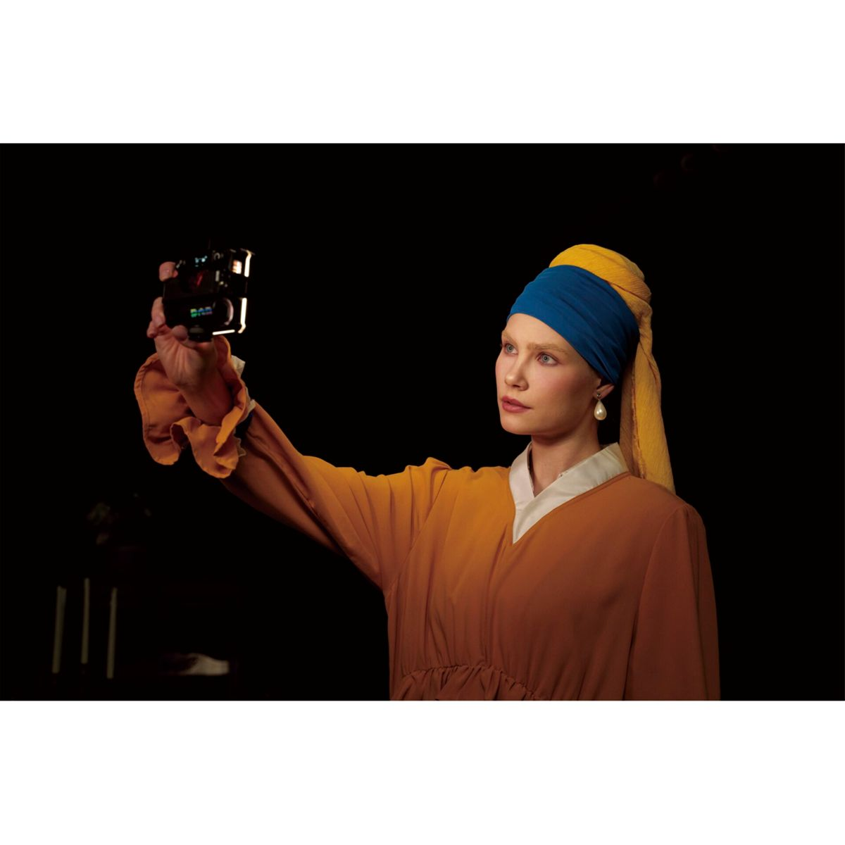 Frau als 'Mädchen mit dem Perlohrring' verkleidet, die ein Selfie mit einer Kamera macht.