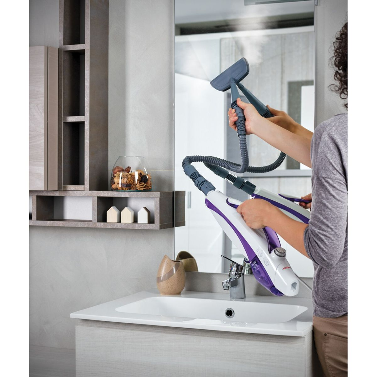 Osoba używa parownicy do czyszczenia lustra w łazience o neutralnej kolorystyce.