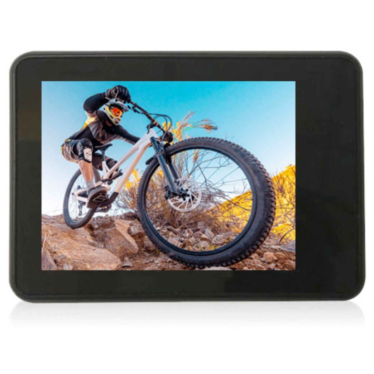 Ekran kamery sportowej pokazuje osobę jeżdżącą na rowerze górskim. Tło to błękitne niebo i skały.