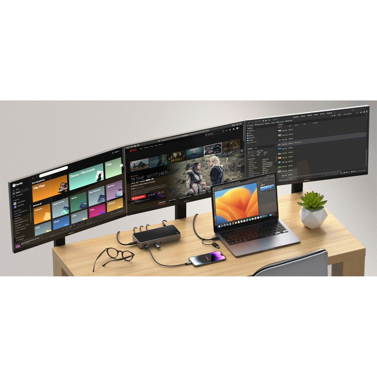 Drei Monitore auf einem Schreibtisch mit Laptop, Telefon und Dockingstation.