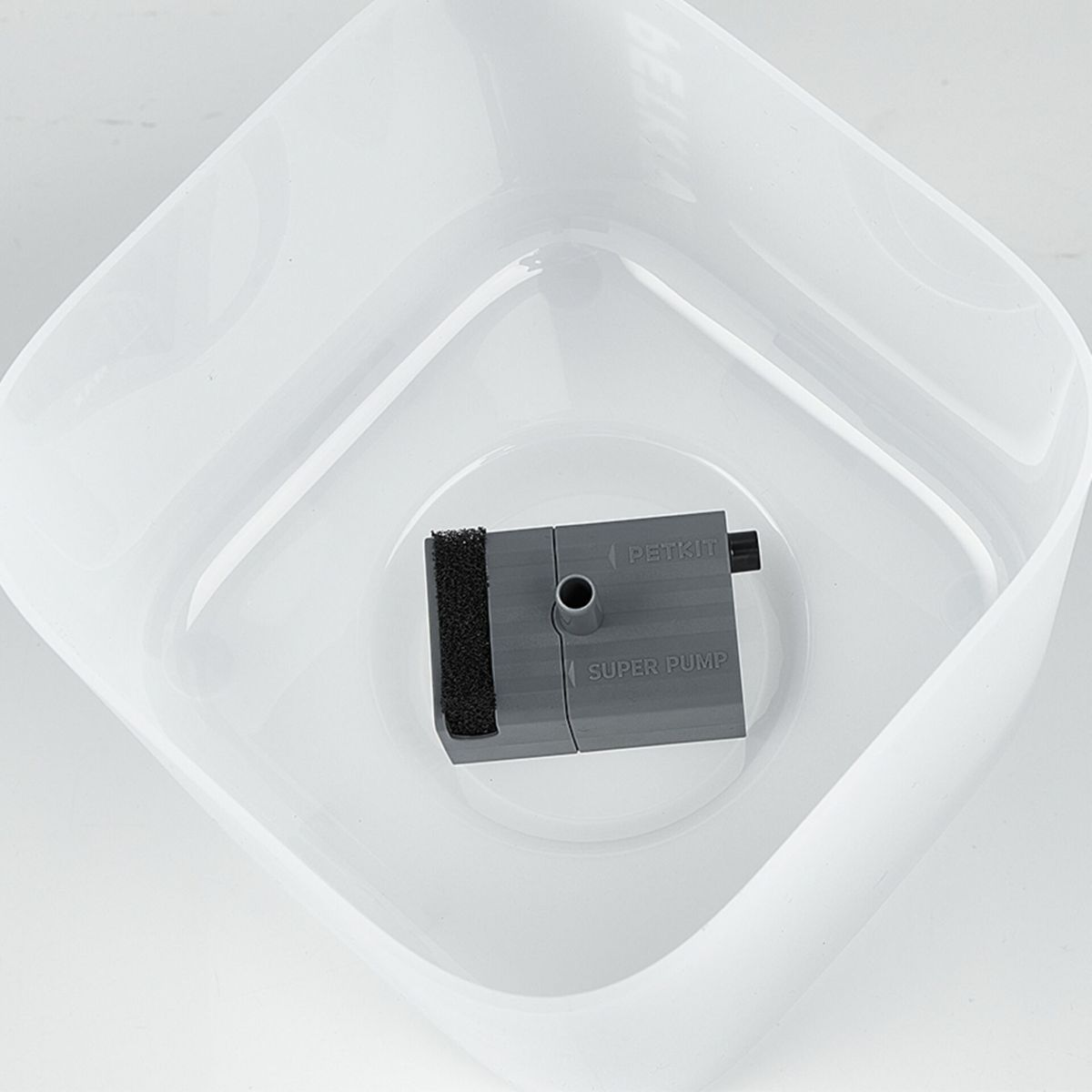 Eine graue Haustier-Wasserfontänenpumpe in einer weißen, quadratischen Schüssel. Die Pumpe trägt die Aufschrift 'Petkit Super Pump'.