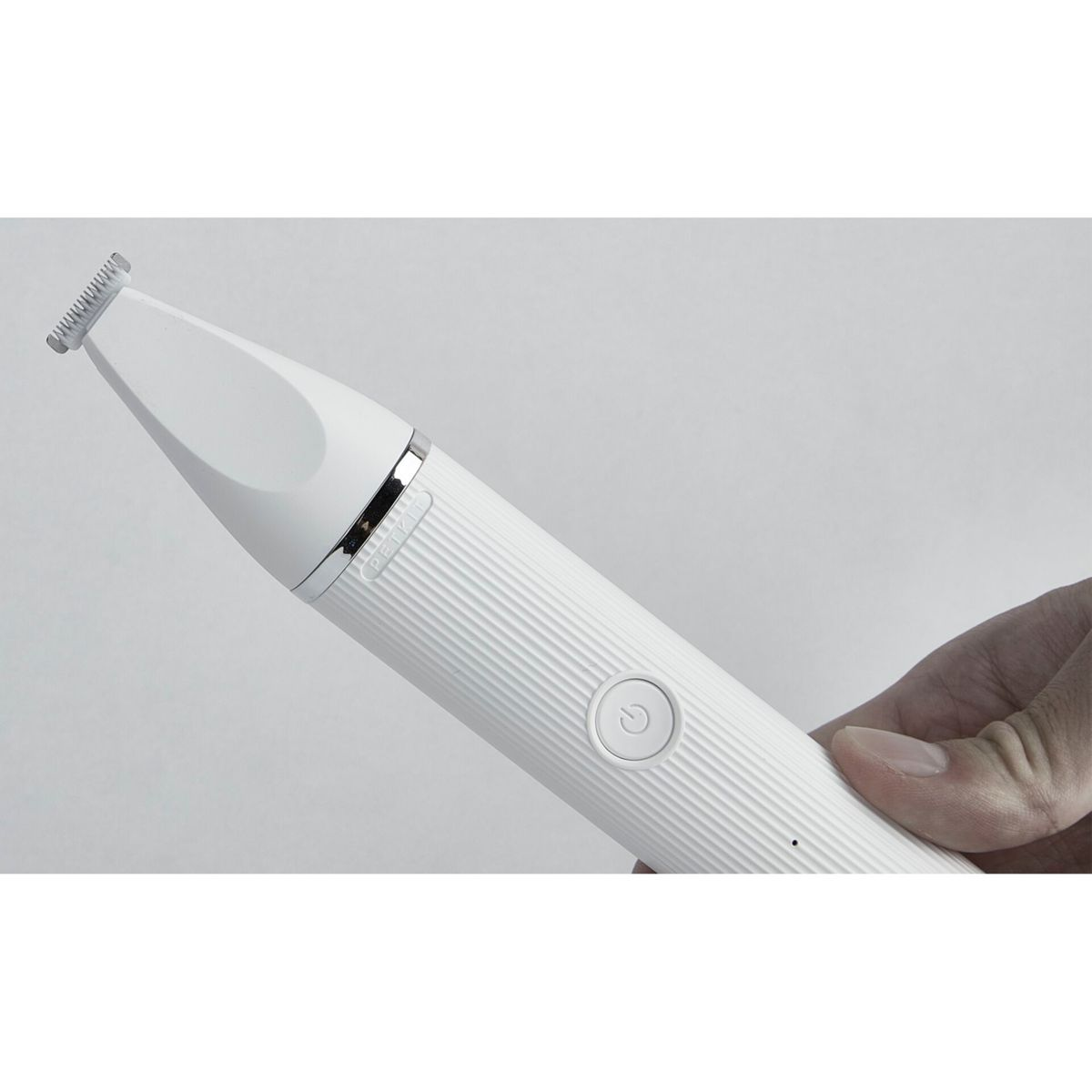 Biała elektryczna maszynka do strzyżenia trzymana w dłoni. Trymer ma przycisk i widoczne ostrze.