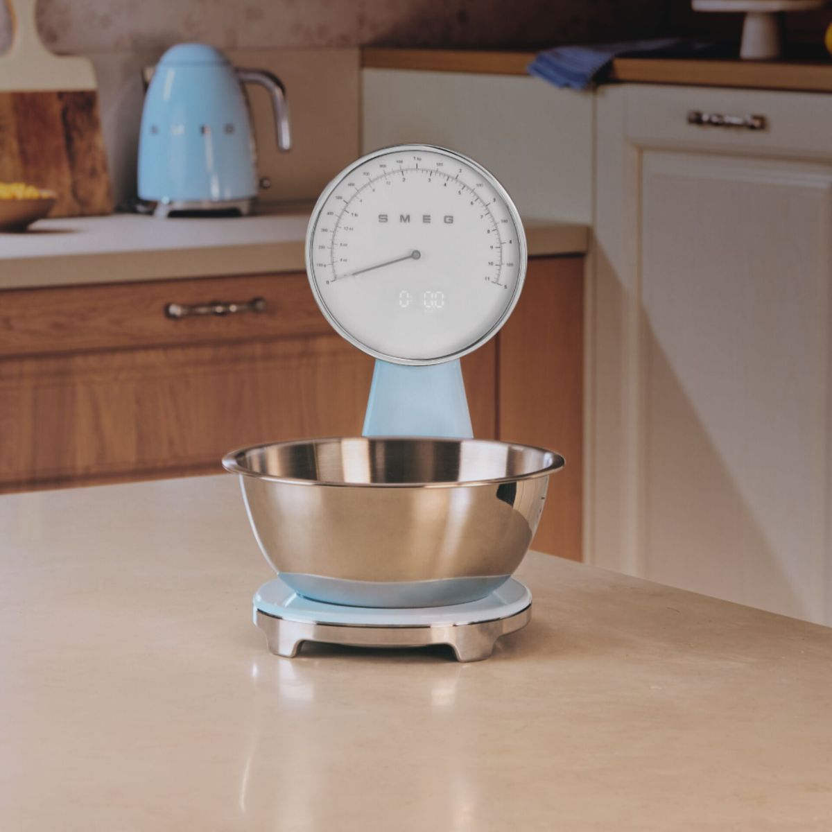 Jasnoniebieska waga kuchenna ze stalową miską na górze. Waga stoi na jasnym blacie.