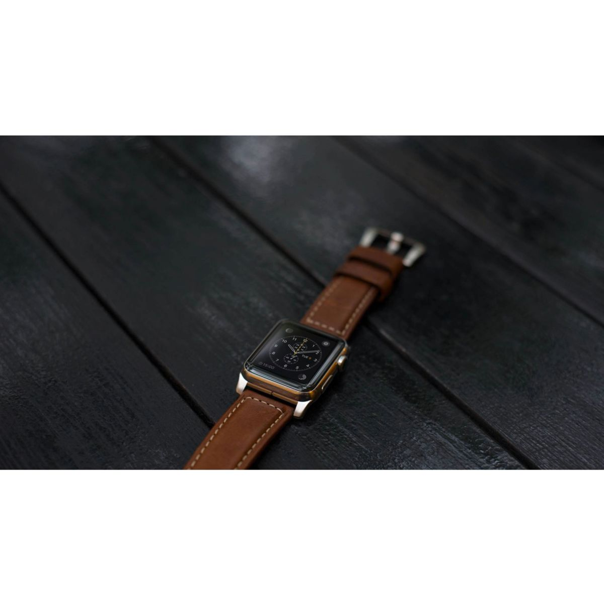 Zegarek z brązowym skórzanym paskiem na czarnej drewnianej powierzchni.