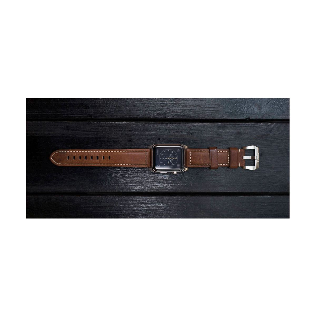 Brązowy skórzany zegarek z prostokątną tarczą, spoczywający na czarnej drewnianej powierzchni.