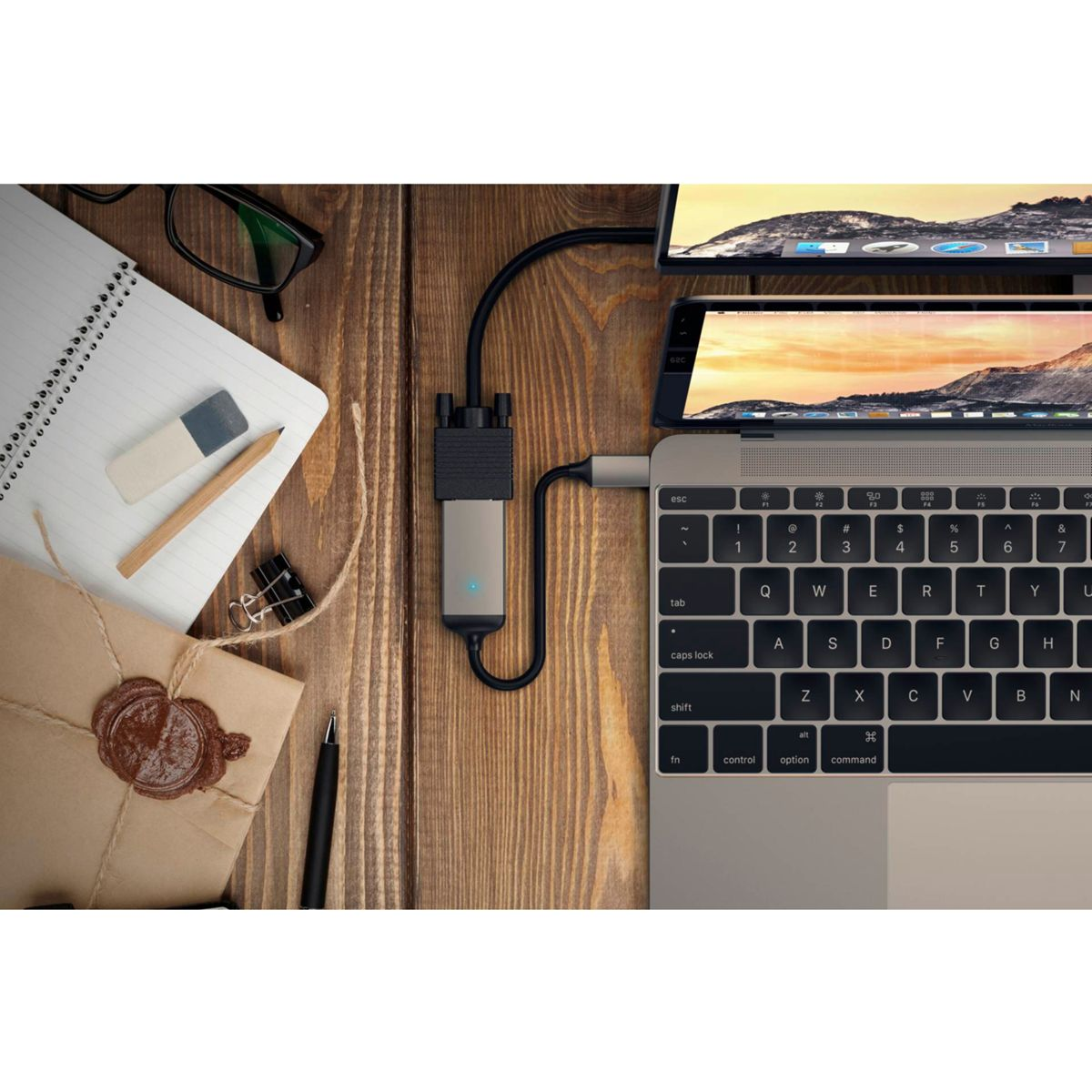Laptop über einen Hub mit mehreren Bildschirmen verbunden, mit Büromaterial auf einem Holzschreibtisch.