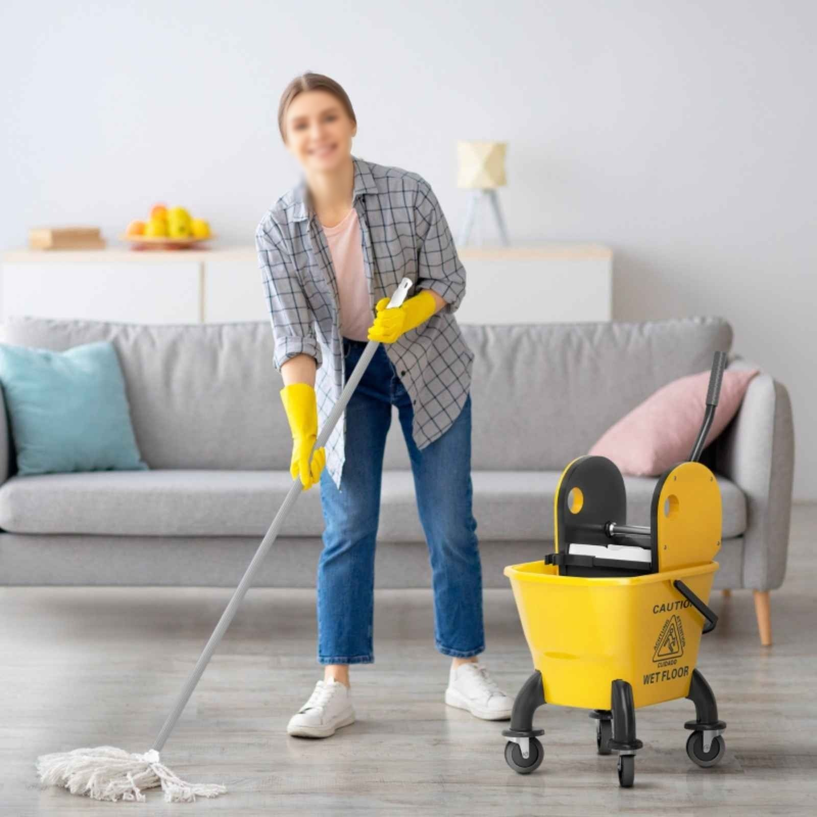 Eine Person wischt einen Boden mit einem gelben Moppeimer. Wohnzimmerhintergrund.