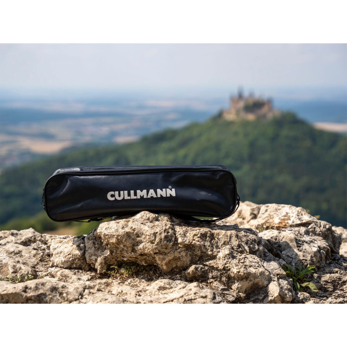 Una borsa nera su rocce con un castello sullo sfondo. Sulla borsa c'è scritto 'CULLMANN'.