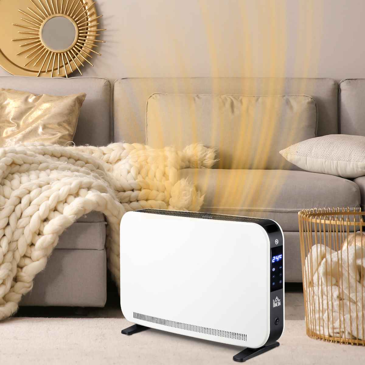 Weißer Elektroheizer mit schwarzem Sockel. Sofa und goldener Spiegel im Hintergrund.