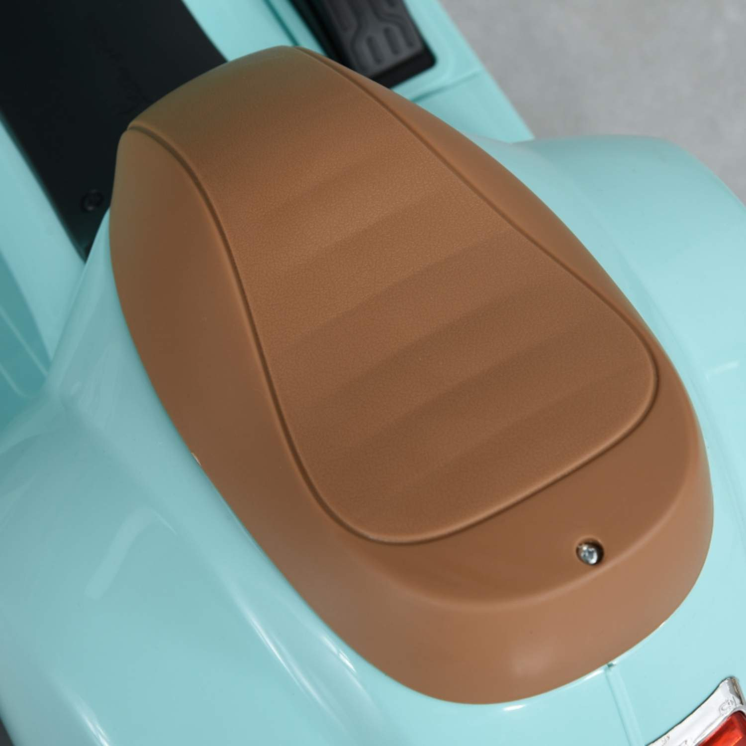 Nahaufnahme eines braunen Motorradsitzes auf einem hellblauen Körper eines Spielzeugmotorrads.